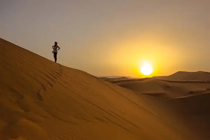 Viajera contemplando el amanecer desde una duna