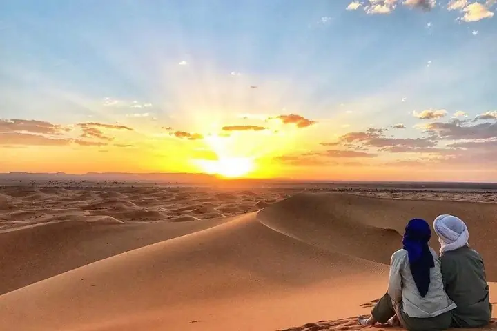 Pareja contemplando el atardecer sobre las dunas de Merzouga