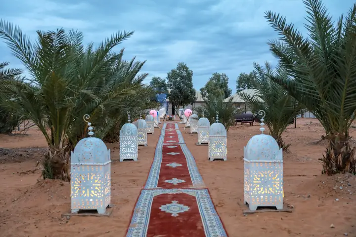 Entrada con faroles y alfombras de un campamento en Erg Chebbi