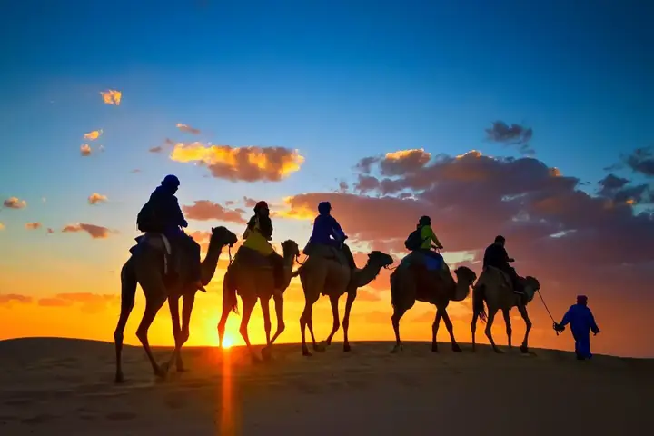 Siluetas de una caravana de camellos al atardecer en Merzouga