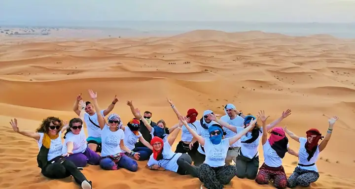 Grupo de viajeros celebrando en las dunas de Merzouga