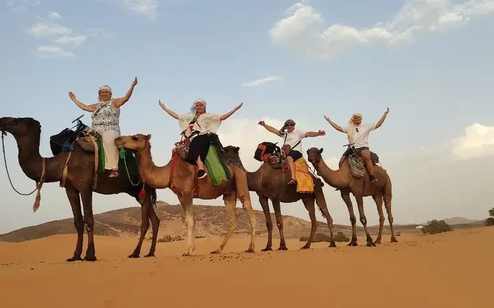 Viajeros felices sobre sus camellos en el desierto de Merzouga