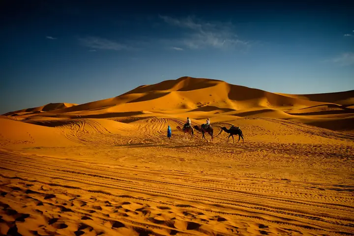 Dunas de Merzouga al anochecer con una pequeña caravana