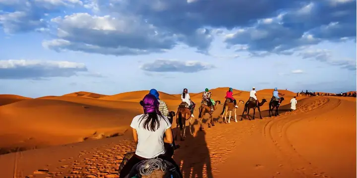 Viajera en camello siguiendo a una caravana por el desierto